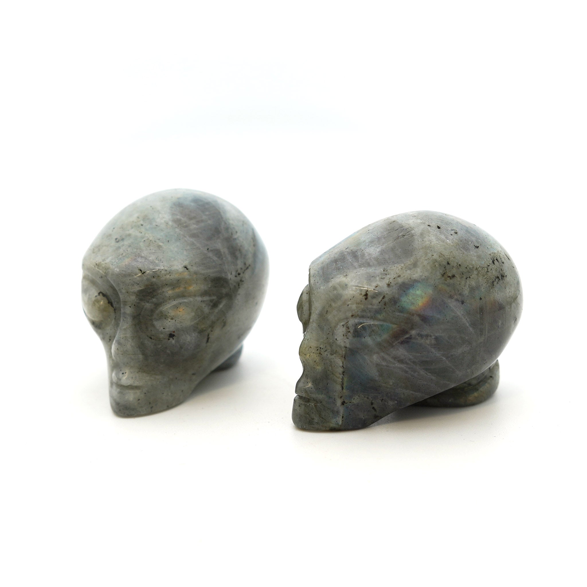 Three Alien heads carved from labradorite on a white background