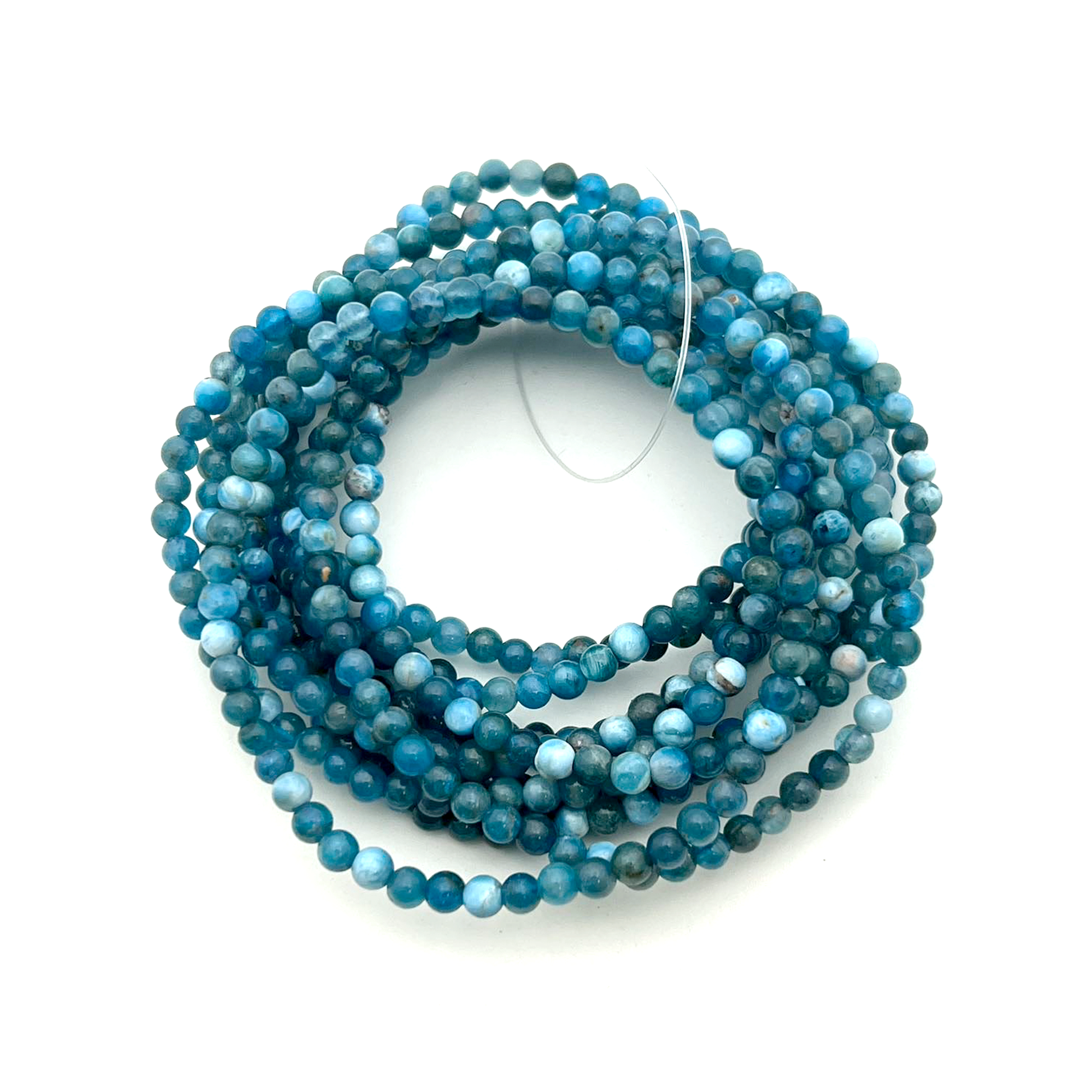 Bundle of round bead bracelets made from blue apatite on a white background