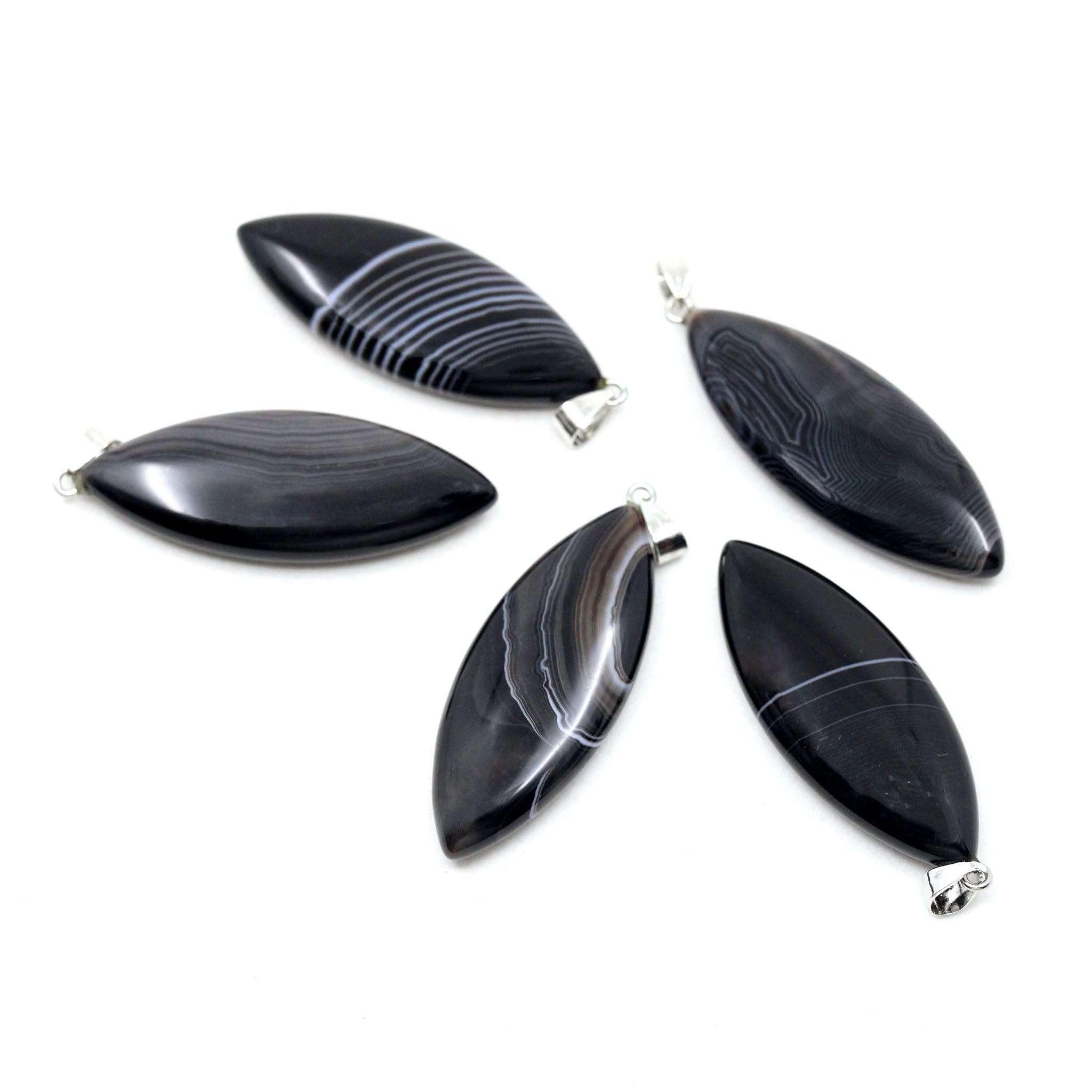 Five surfboard shaped pendants made from Black Banded Agate on a white background. 