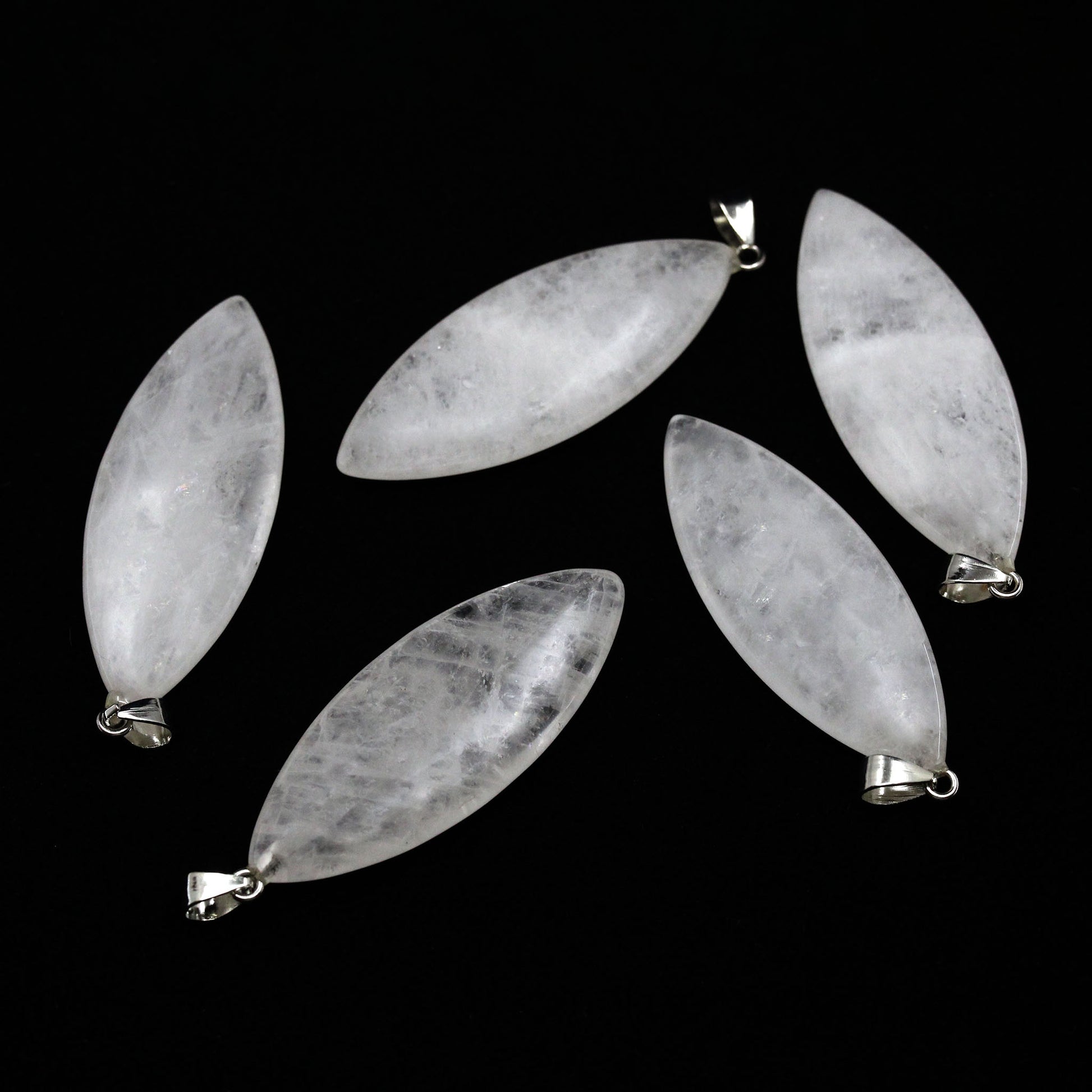 Five surfboard shaped pendants made from quartz on a white background. 