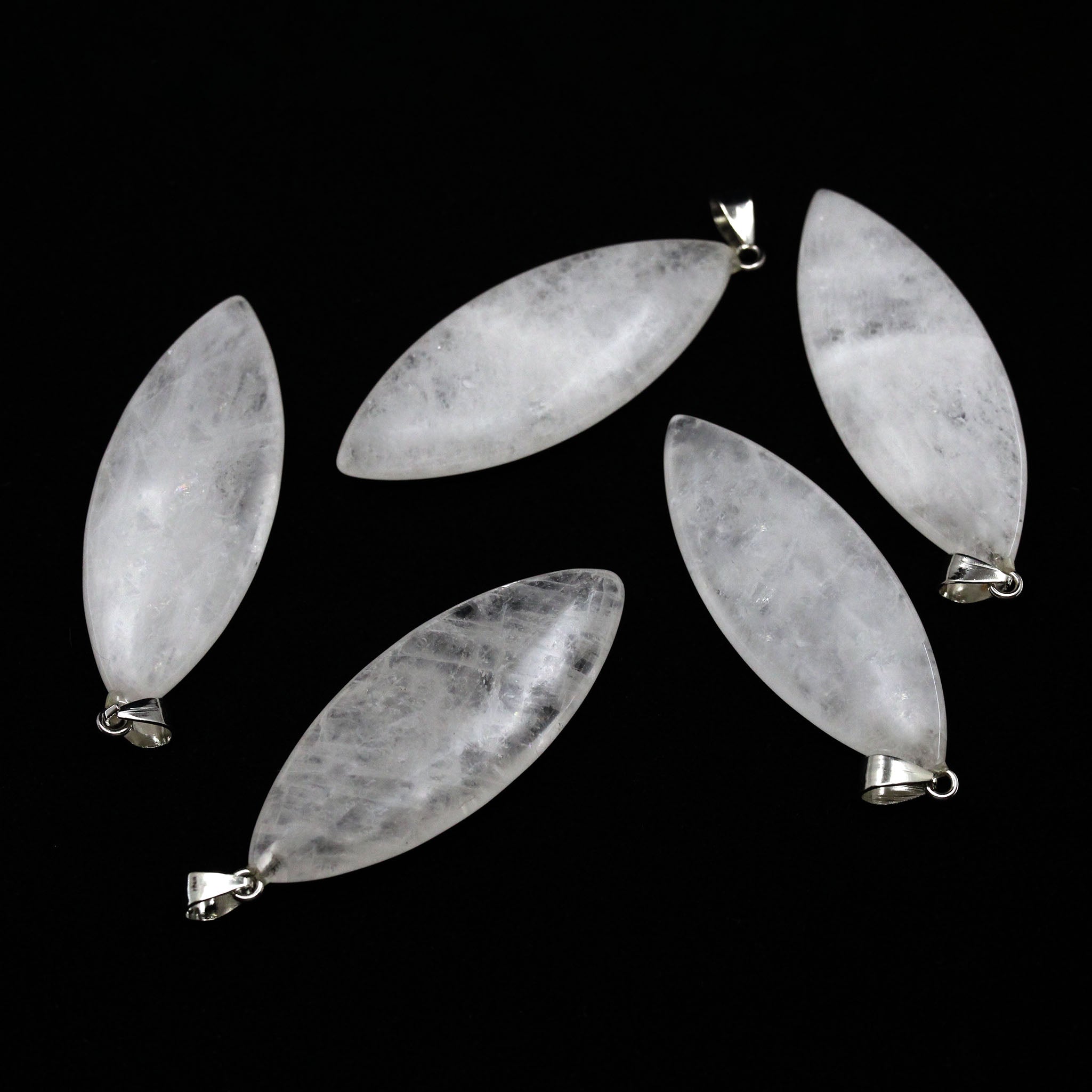 Five surfboard shaped pendants made from quartz on a white background. 