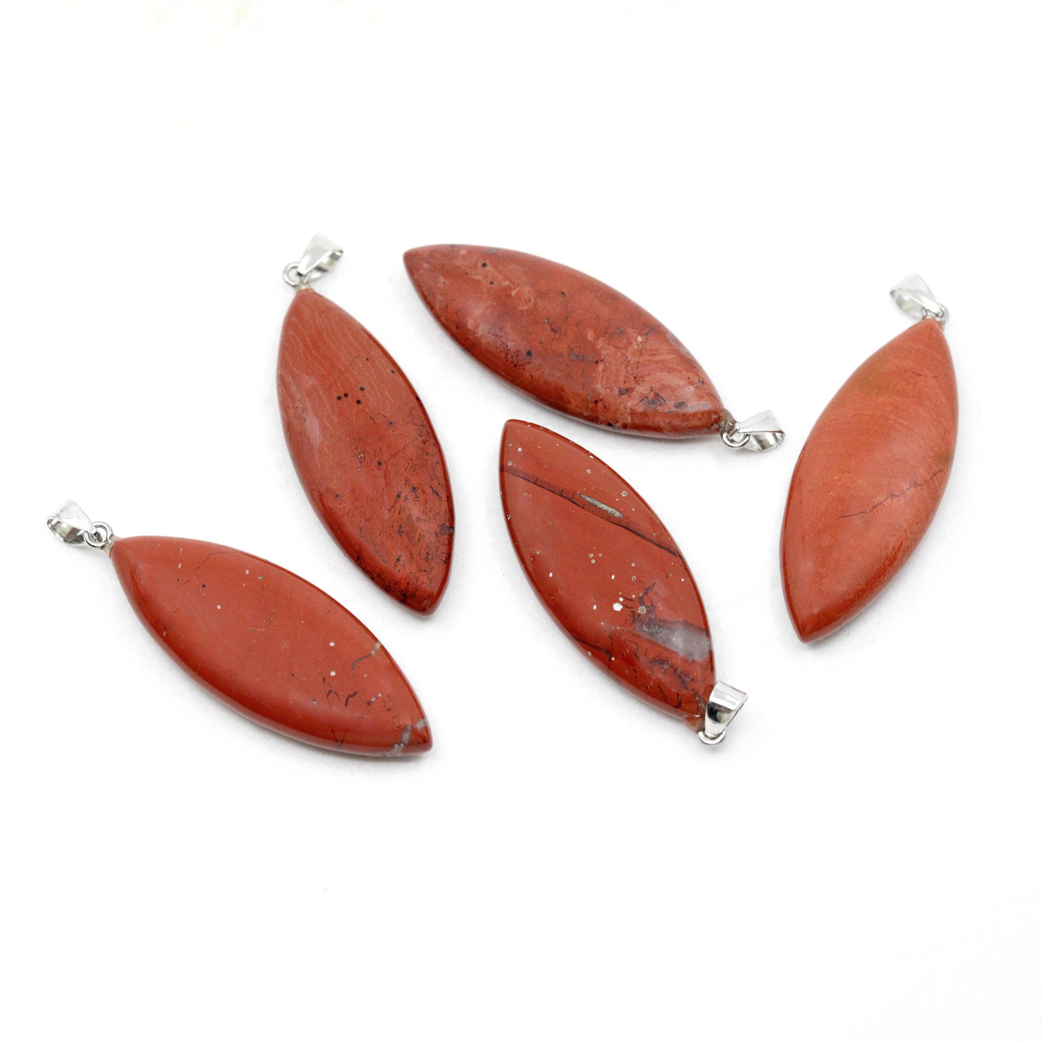 Five pendants made from red jasper with silver clasps on a white background