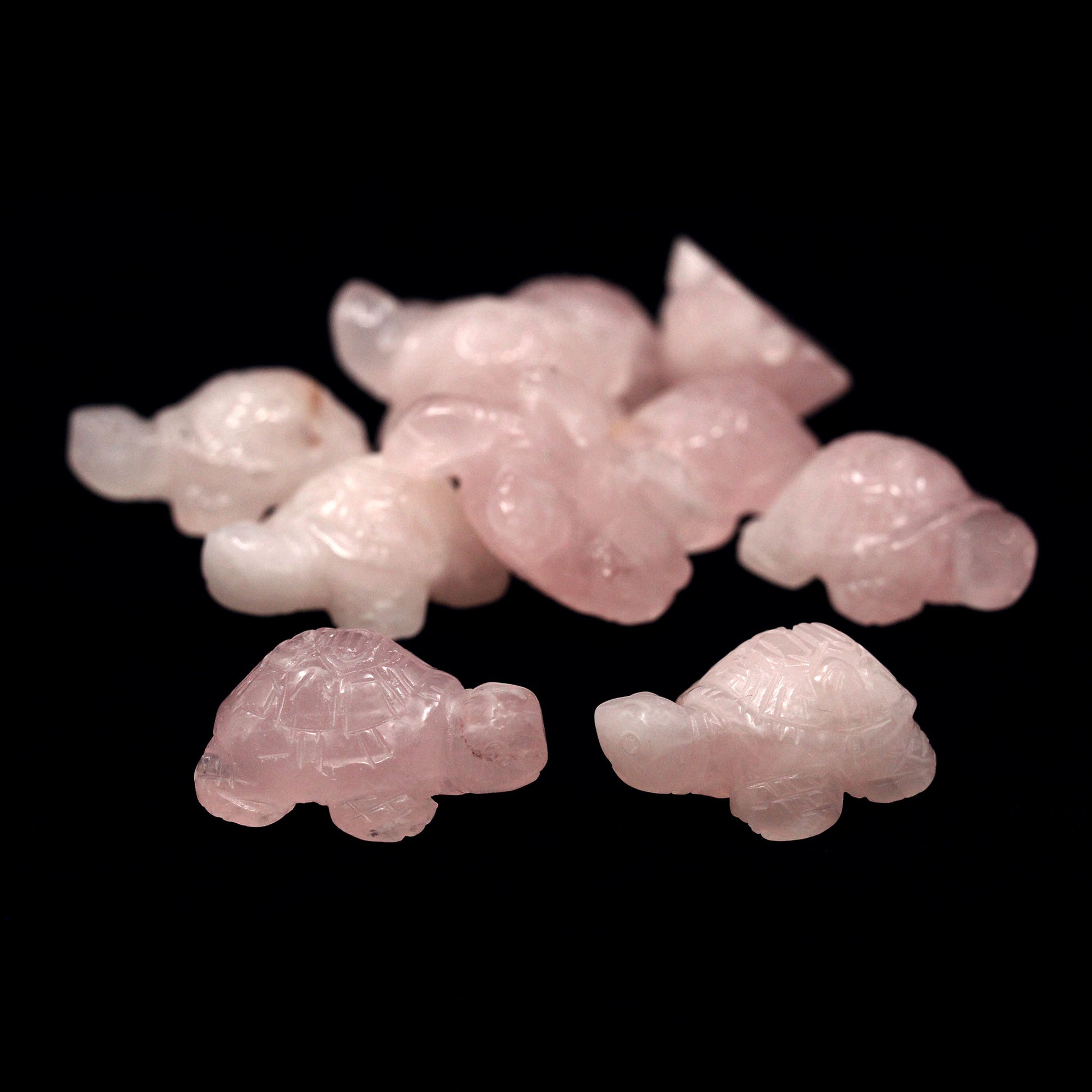 Pink turtle-shaped carvings made from Rose Quartz on a black background